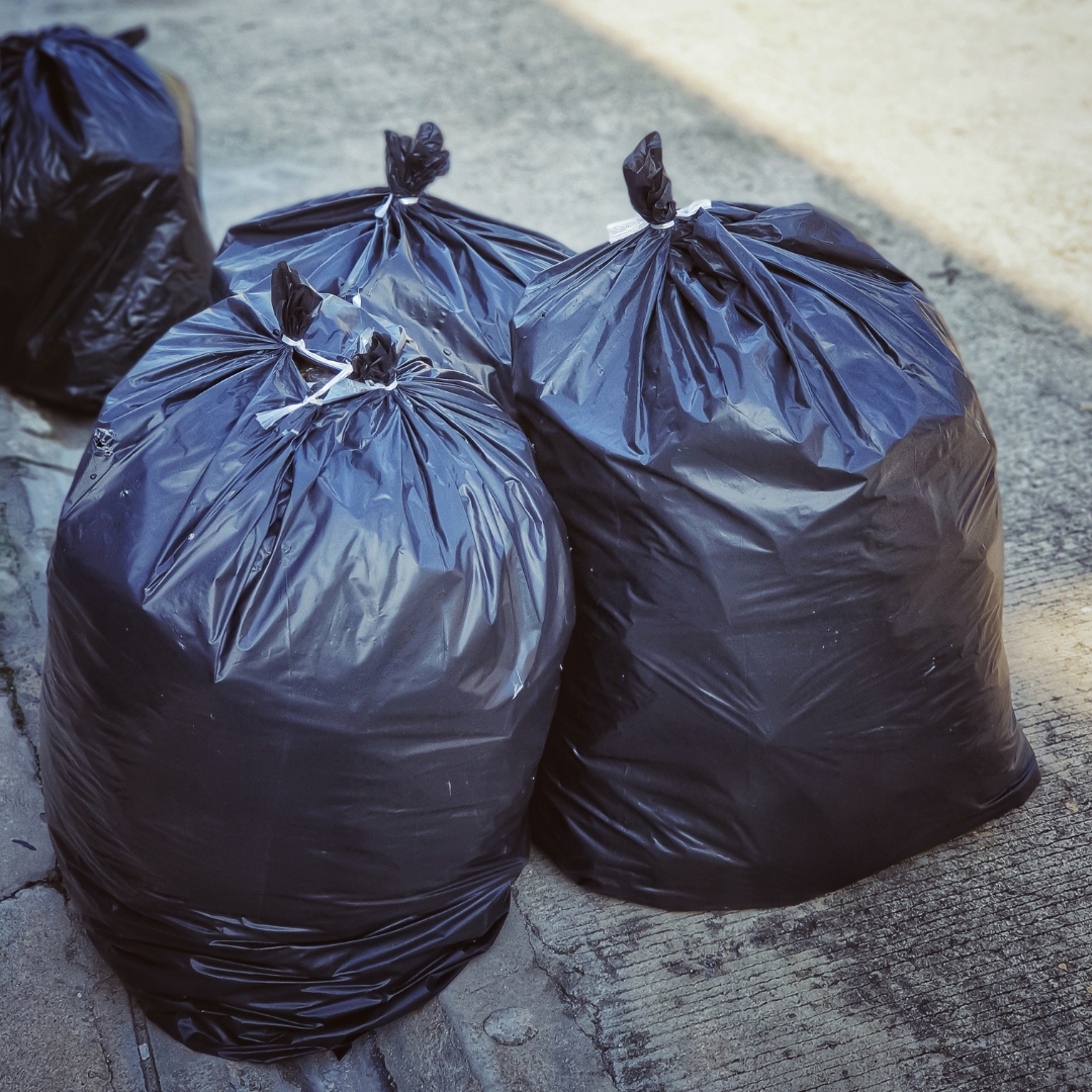 Four black trash bags out on the curb